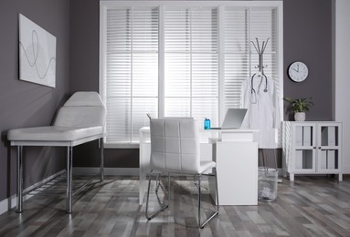 Photo of Modern medical office interior with doctor's workplace and examination table