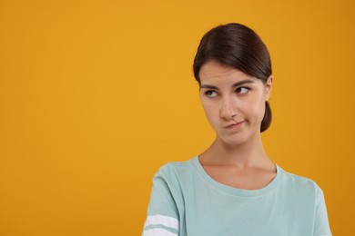 Photo of Portrait of resentful woman on orange background, space for text