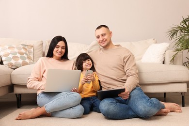 Photo of Happy family with gadgets on floor at home