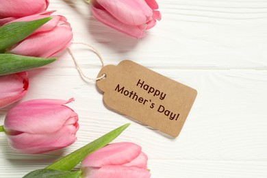 Image of Happy Mother's Day greeting label and beautiful tulip flowers on white wooden table