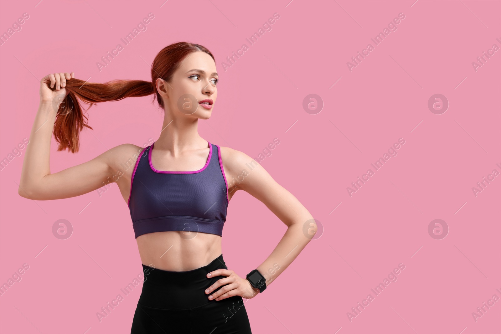 Photo of Young woman in sportswear on pink background, space for text
