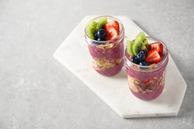 Image of Tasty dessert with acai smoothie, granola and berries on marble table. Space for text