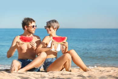 Photo of Young couple with watermelon slices on beach
