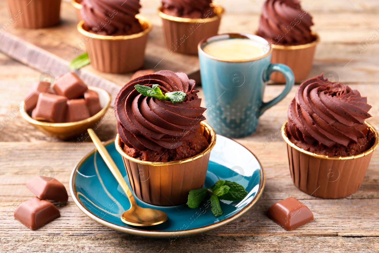 Photo of Delicious cupcakes with mint and chocolate pieces on wooden table
