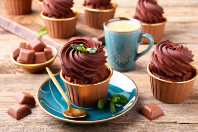 Photo of Delicious cupcakes with mint and chocolate pieces on wooden table