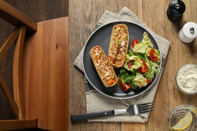 Photo of Pieces of tasty strudel with chicken, vegetables and salad served on wooden table, flat lay