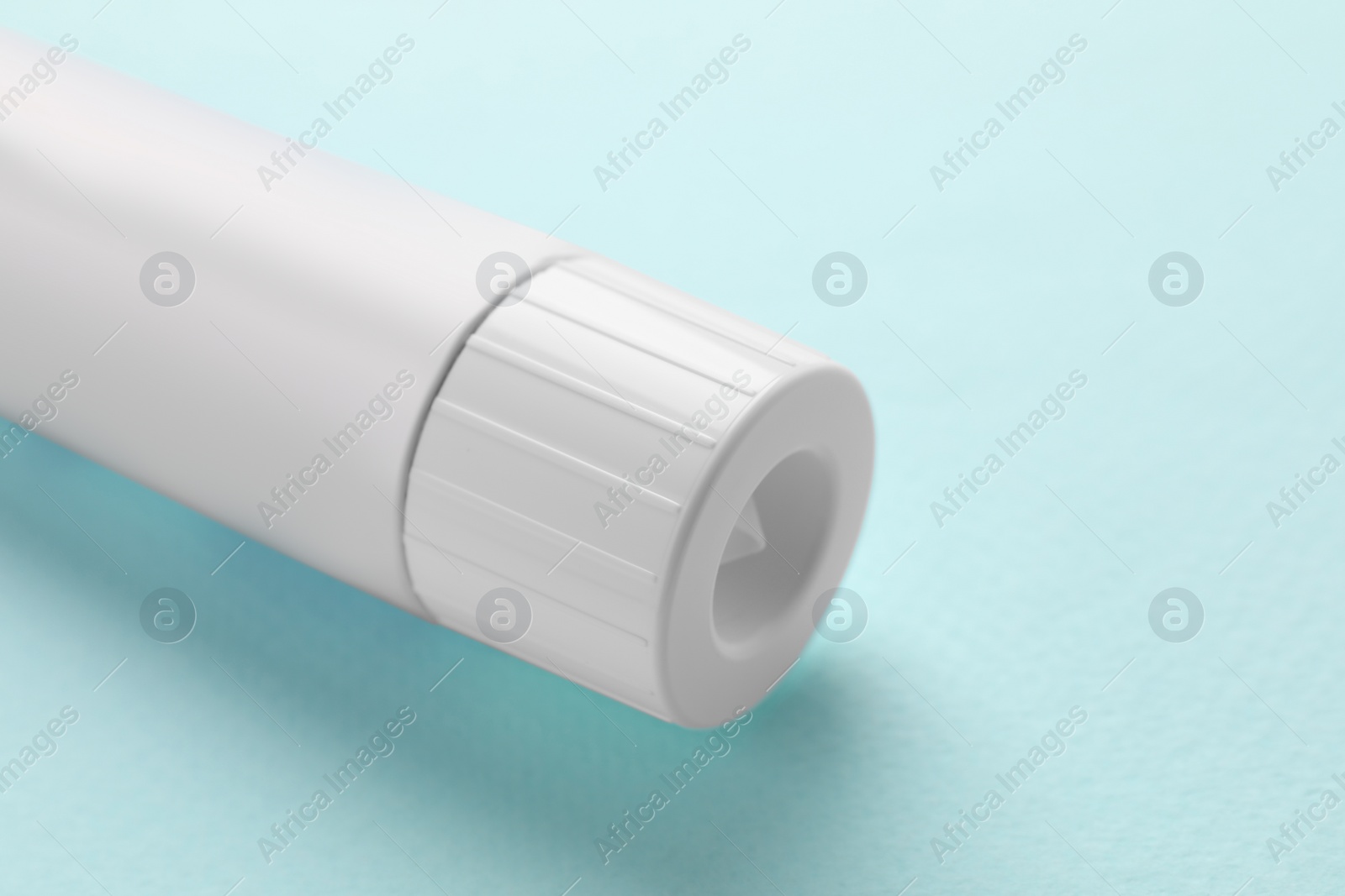 Photo of Tube of ointment on light blue background, closeup. Space for text