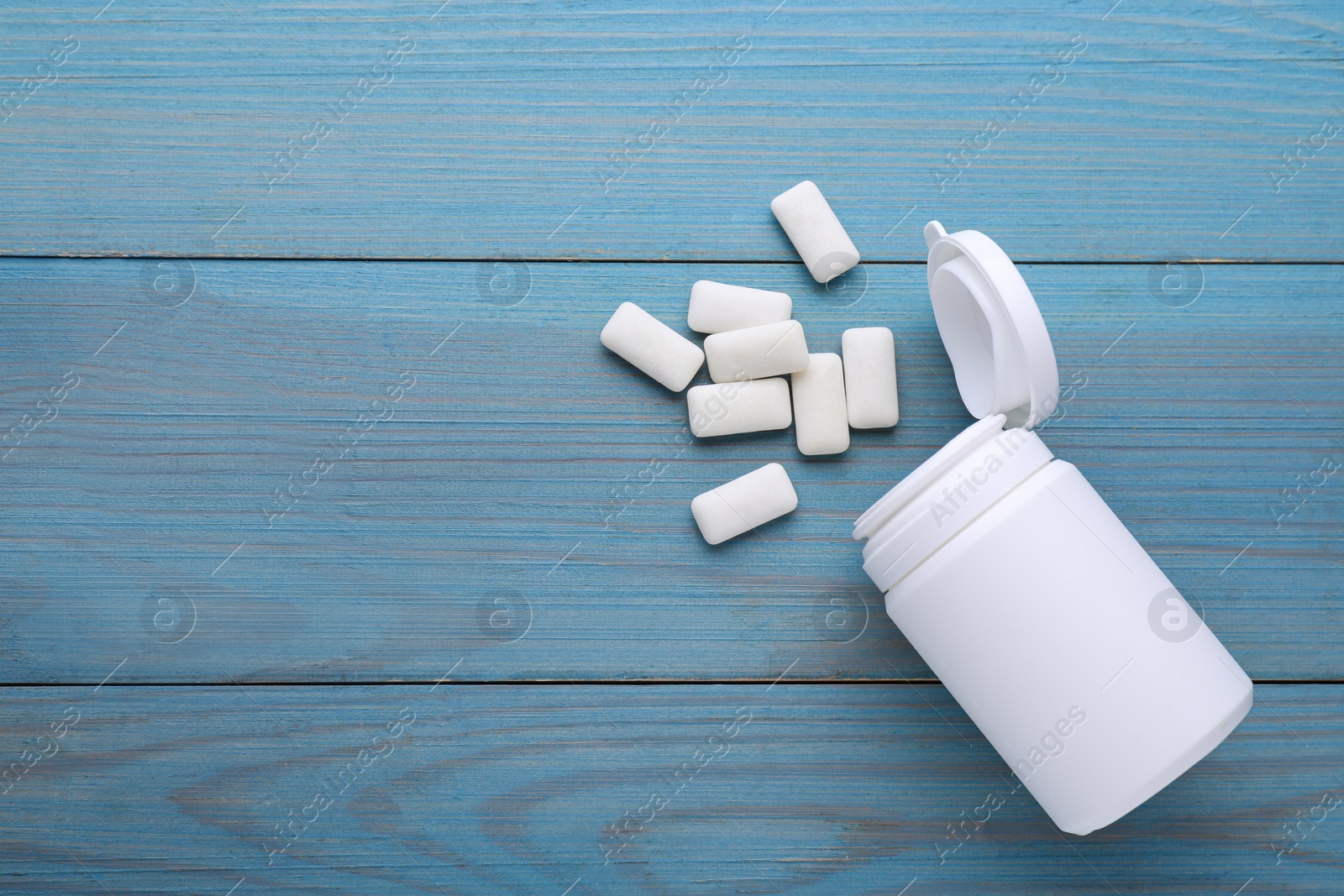 Photo of Jar with chewing gums on light blue wooden table, flat lay. Space for text