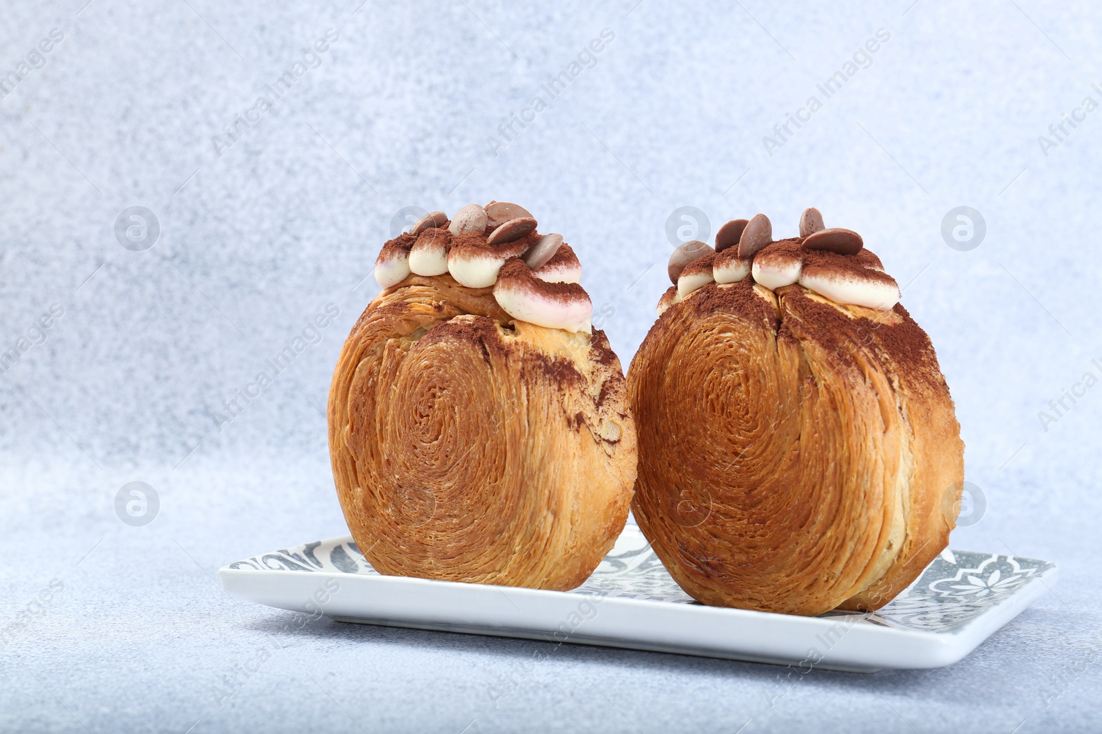 Photo of Tasty puff pastry. Supreme croissants with chocolate chips and cream on grey background, closeup. Space for text