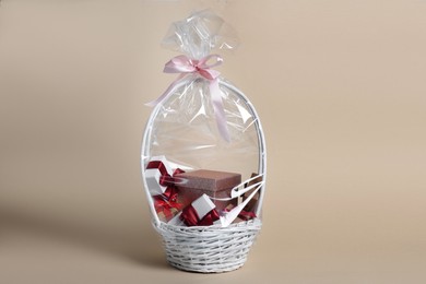 Wicker basket full of gift boxes on beige background