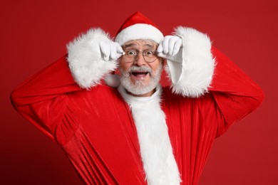 Photo of Merry Christmas. Excited Santa Claus on red background