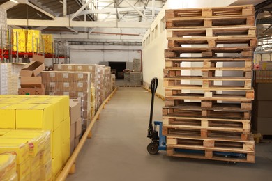 Image of Modern manual forklift with wooden pallets in warehouse