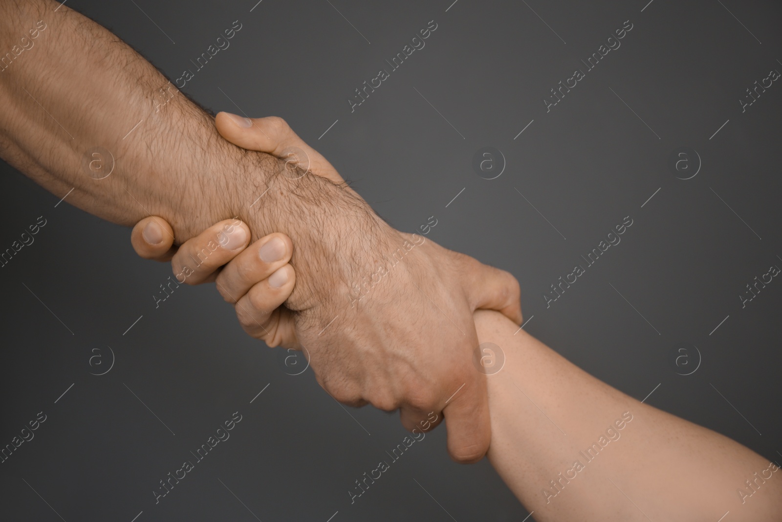 Photo of Men holding hands together on grey background. Unity concept