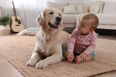 Photo of Cute little baby with adorable dog on floor at home