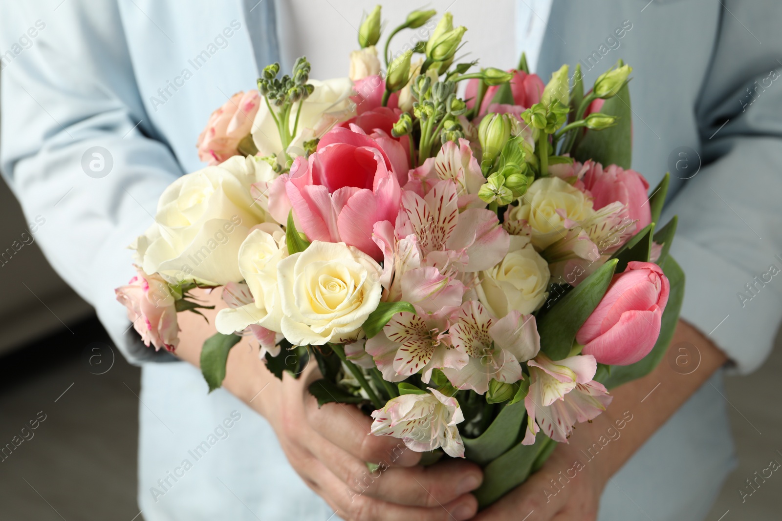 Photo of Man holding bouquet of beautiful flowers indoors, closeup