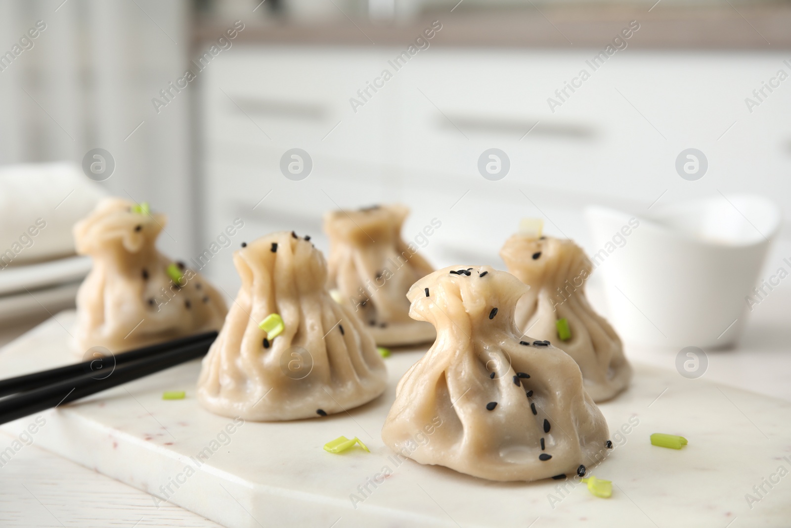 Photo of Board with tasty baozi dumplings and chopsticks on table, closeup