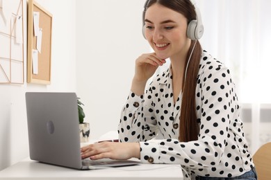 E-learning. Young woman using laptop during online lesson at table indoors