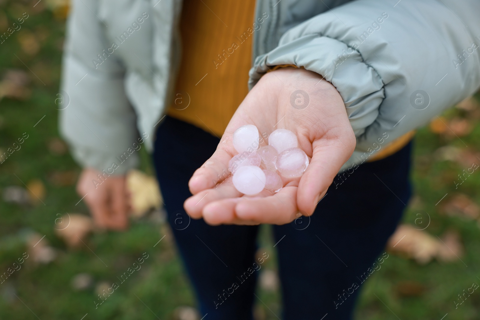 Photo of Woman holding hail grains after thunderstorm outdoors, closeup