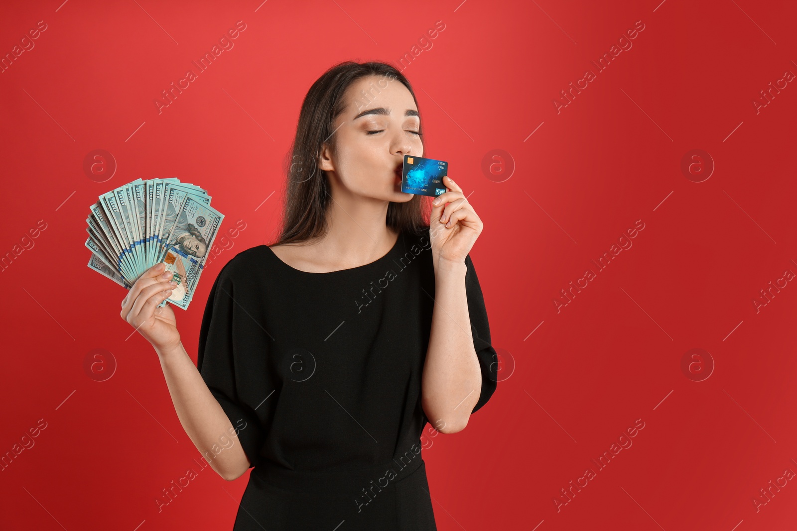 Photo of Emotional young woman with money and credit card on crimson background. Space for text