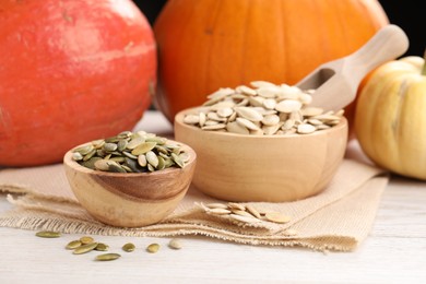 Photo of Bowls with seeds and fresh pumpkins on light wooden table