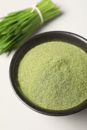 Photo of Wheat grass powder in bowl on light table, closeup