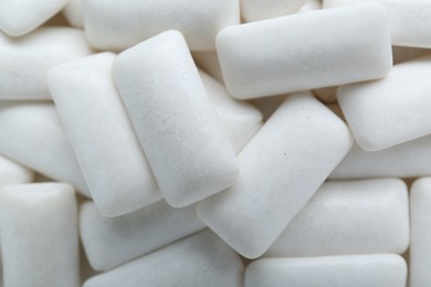 Photo of Tasty white chewing gums as background, top view