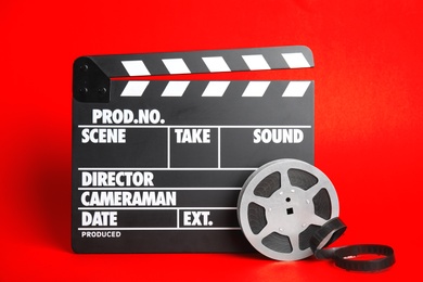 Photo of Clapperboard and reel on color background. Cinema production