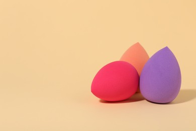 Photo of Many different makeup sponges on beige background, space for text