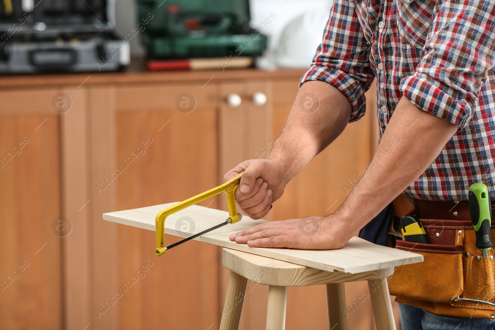 Photo of Man working with hand saw indoors, closeup. Home repair