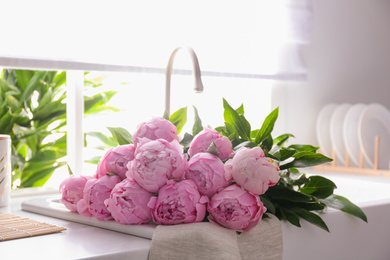 Photo of Bouquet of beautiful pink peonies in kitchen sink