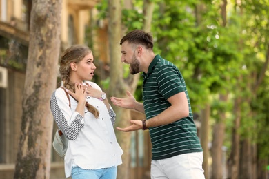 Photo of Young couple arguing on street. Problems in relationship