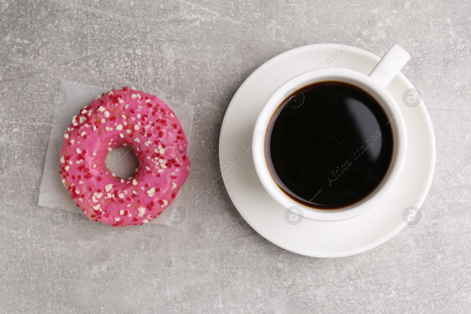 Photo of Tasty frosted donut and cup of coffee on light grey table, flat lay