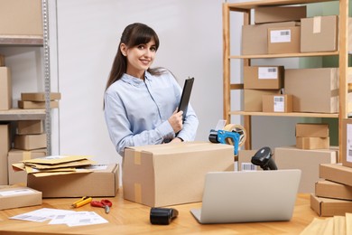 Parcel packing. Post office worker with clipboard at wooden table indoors