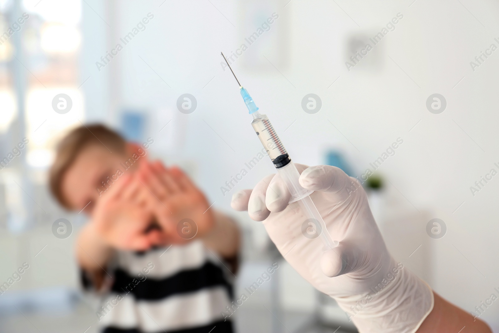Photo of Doctor with syringe and child on background. Vaccination day
