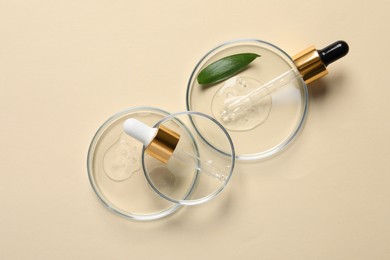 Photo of Petri dishes with samples of cosmetic oil, pipettes and green leaf on beige background, flat lay
