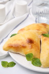 Photo of Delicious samosas and basil on white table