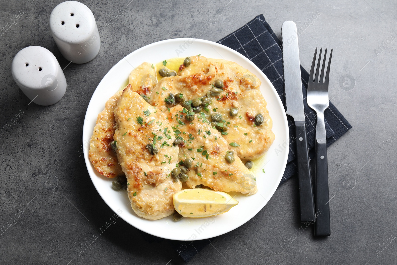 Photo of Delicious chicken piccata with herbs served on grey table, flat lay