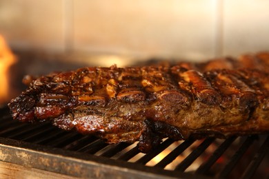 Photo of Grilling grate with tasty pork ribs in oven, closeup