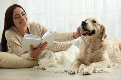 Young woman with book and her Golden Retriever at home. Adorable pet