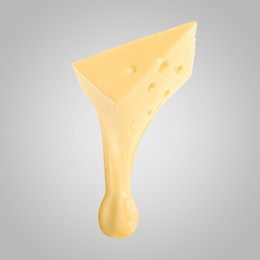 Tasty cheese stretching in air on grey background