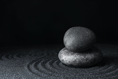 Photo of Spa stones on black sand with beautiful pattern, space for text. Zen and harmony