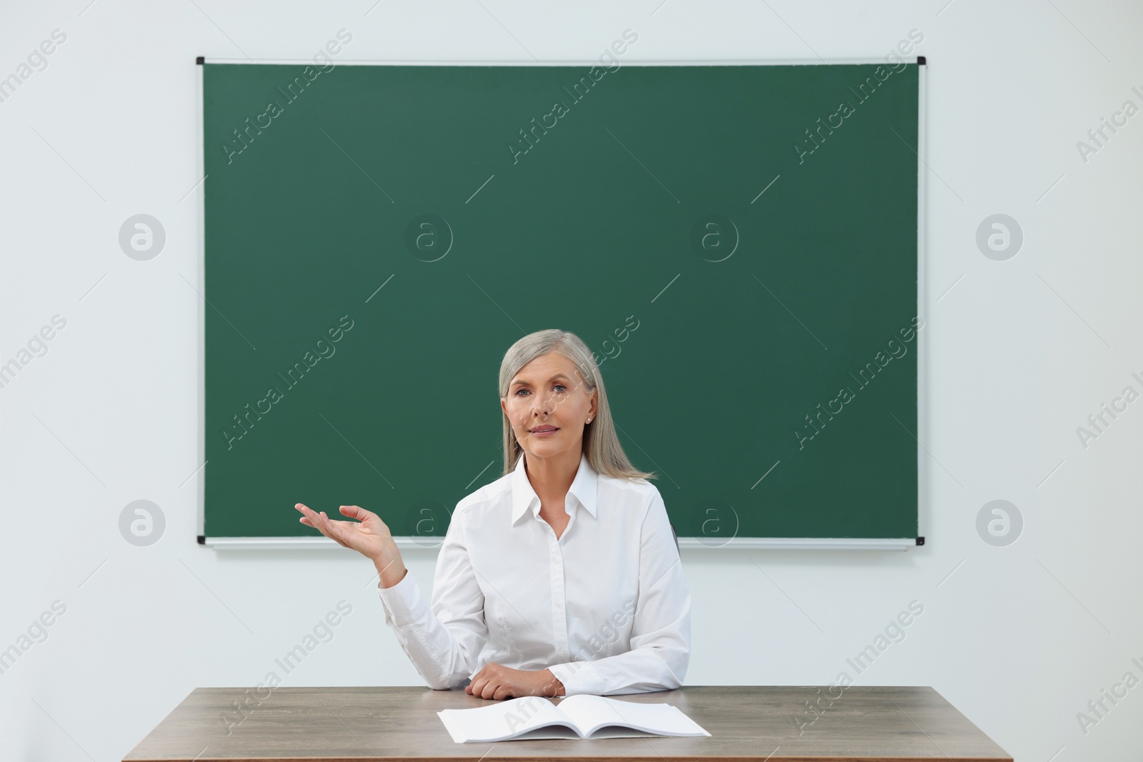 Photo of Professor giving lecture at desk in classroom