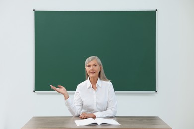 Professor giving lecture at desk in classroom