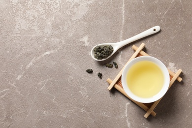 Photo of Cup of Tie Guan Yin oolong and spoon with tea leaves on table, top view. Space for text
