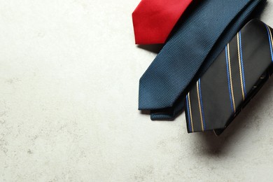 Photo of Different neckties on light textured table, flat lay. Space for text