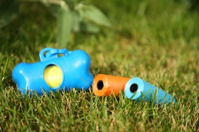 Photo of Rolls of colorful dog waste bags on green grass outdoors