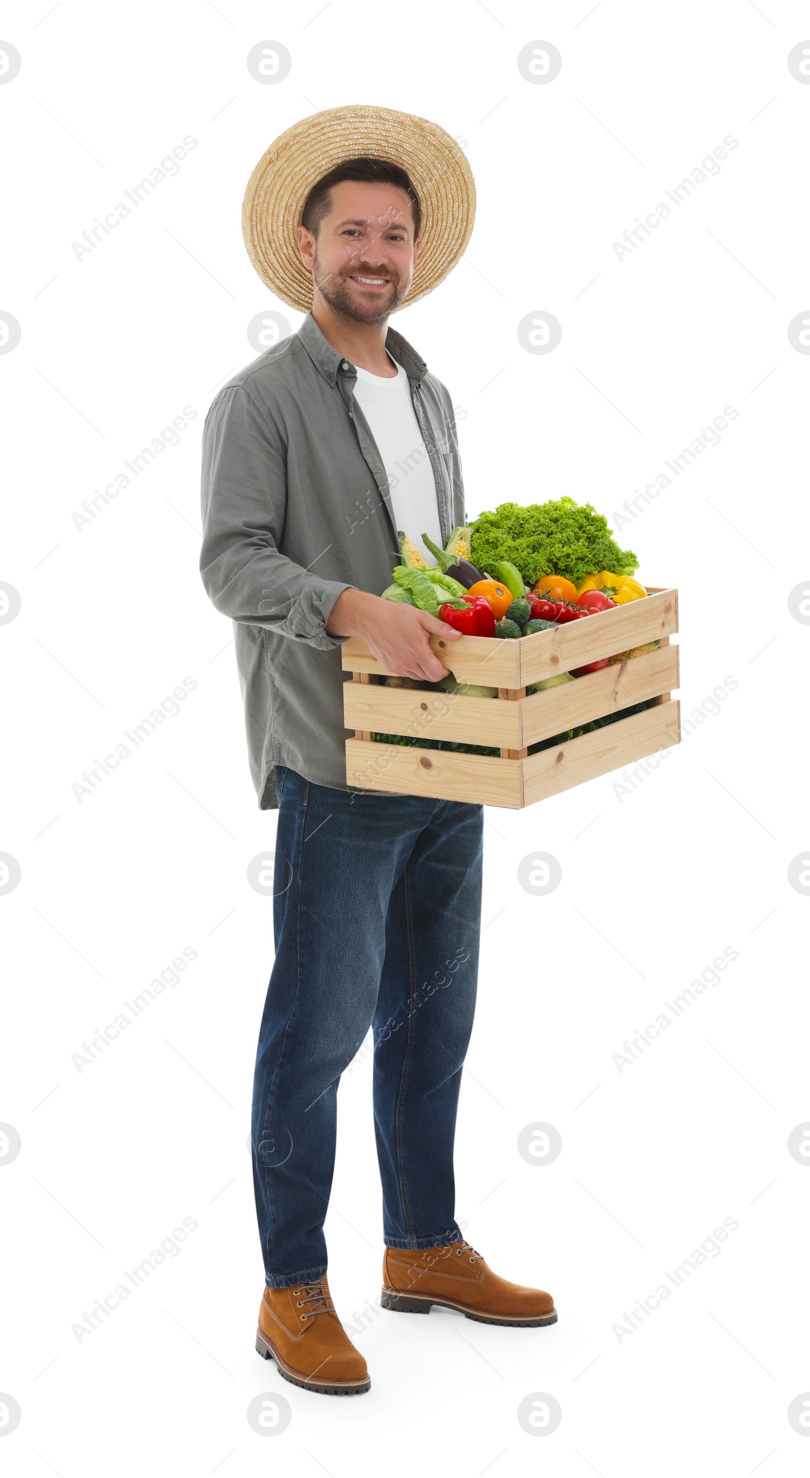 Photo of Harvesting season. Happy farmer holding wooden crate with vegetables on white background