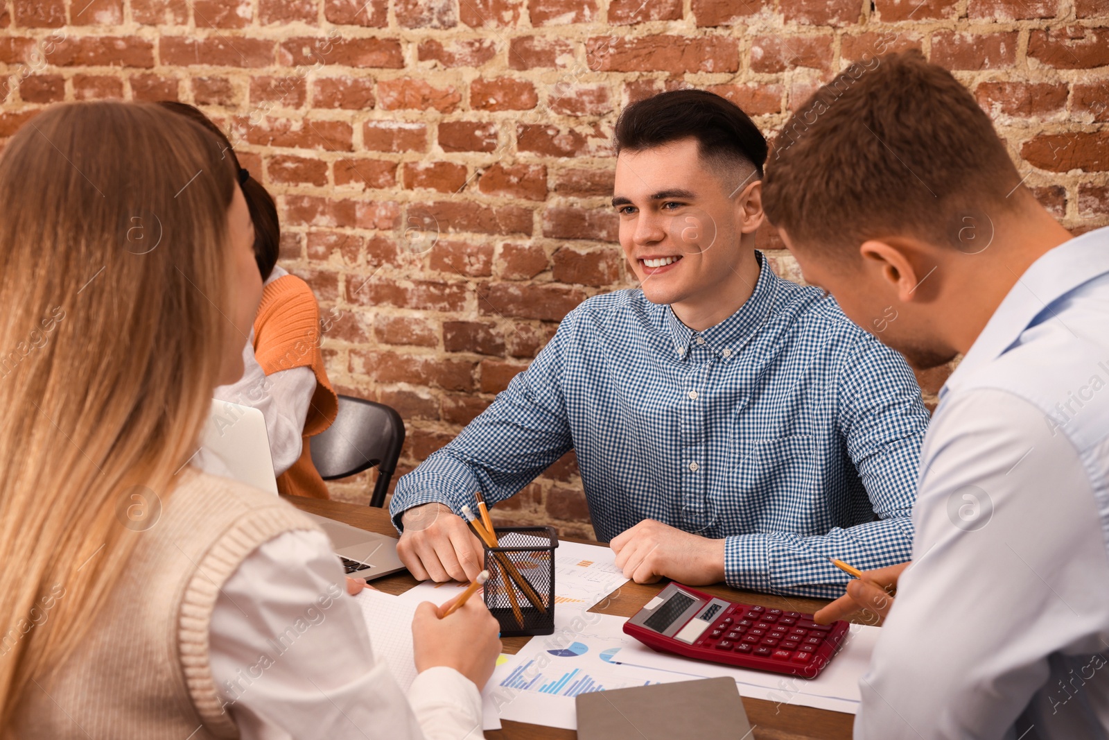 Photo of Team of employees working together at wooden table in office