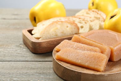 Tasty sweet quince paste, fresh fruits and bread on wooden table, closeup. Space for text
