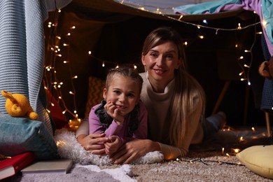 Photo of Mother and her daughter with laptop in play tent at home